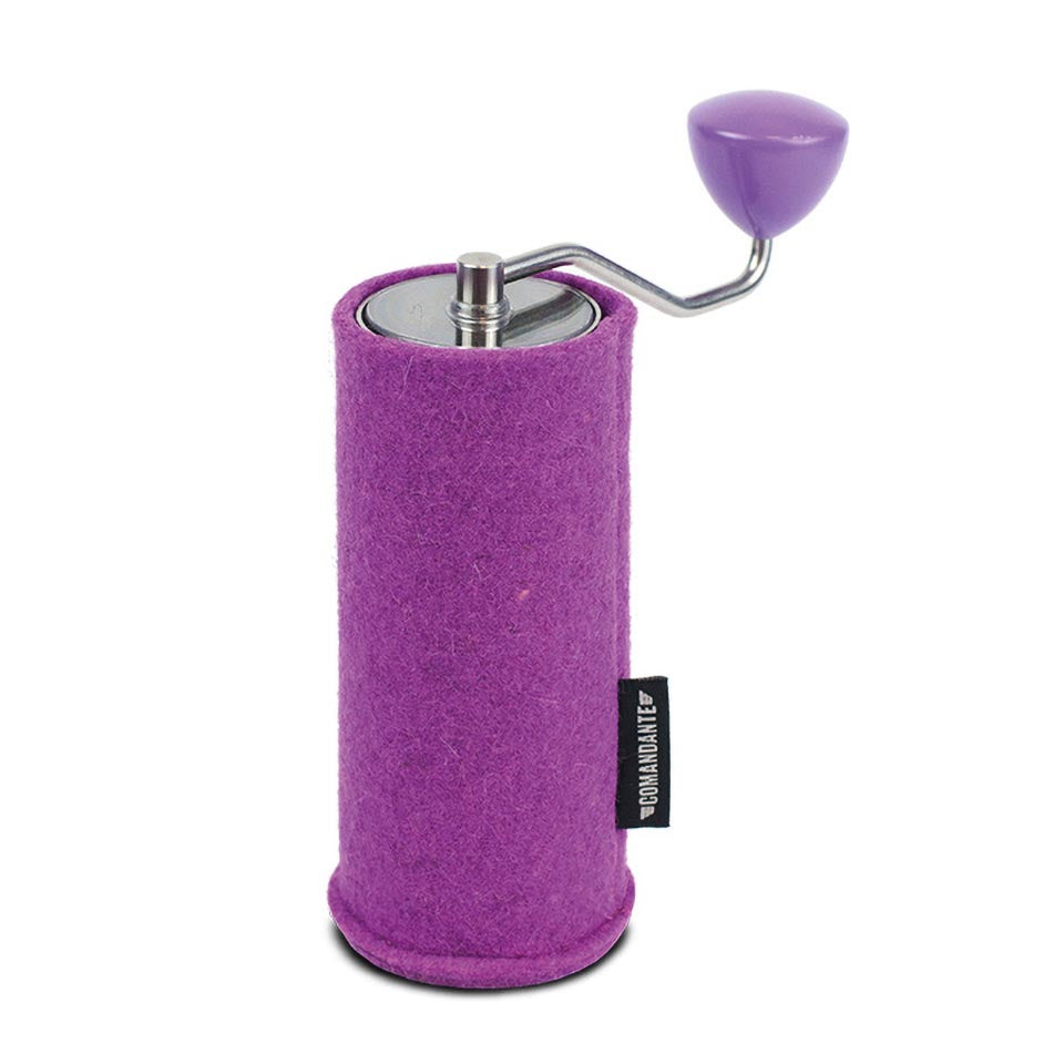 Comandante C40 Filt Sleeve i Mallow er en lilla manuel kaffekværn med et håndsving, med en Kashmir-inspireret filtlignende krop og en slank metaltop. Et lille sort mærke tilføjer elegance til siden.
