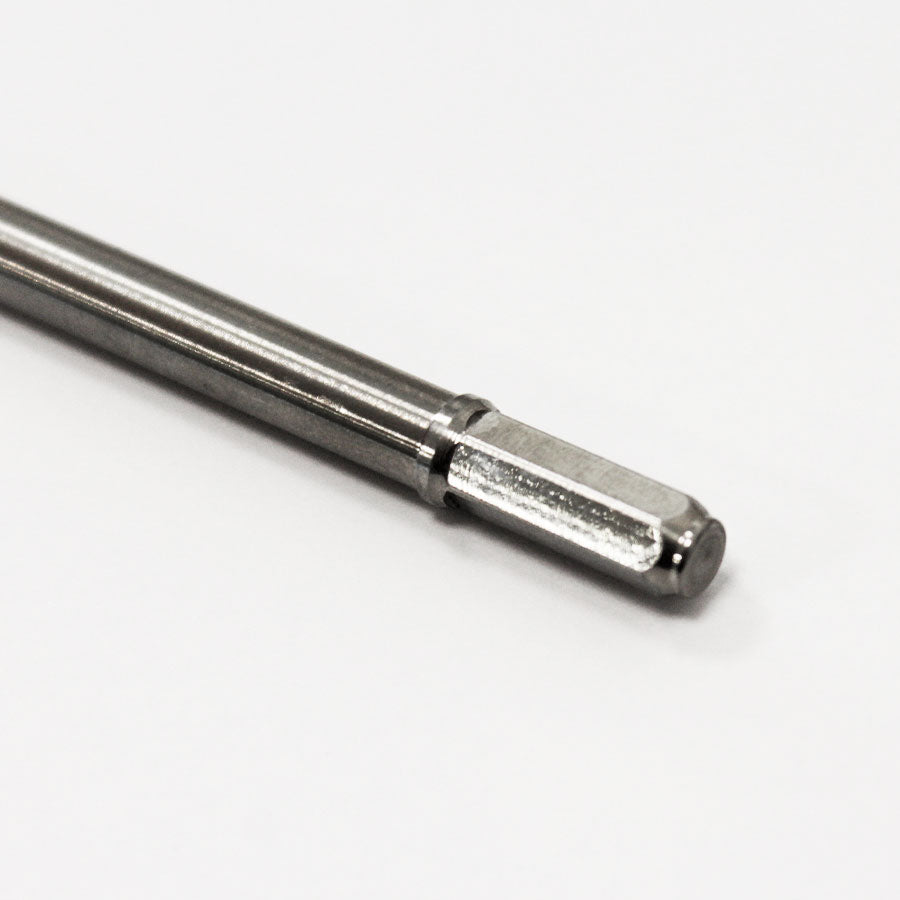 Et nærbillede af Comandante RX35 Red Clix Center Aksel boret med et sekskantet skaft på en hvid baggrund. Dens skinnende overflade reflekterer lyset, mens den glatte cylindriske krop strækker sig til dens afskårne ende.