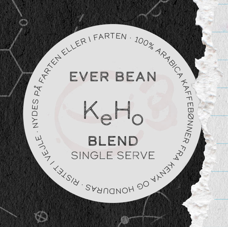 En rund etiket til "Single Serve, KeHo" kaffe fra EverBean ApS. med 100% Arabica Honduras kaffe. Dansk og engelsk tekst vises på en mørk baggrund med en revet højre kant, der fremhæver denne unikke blanding.