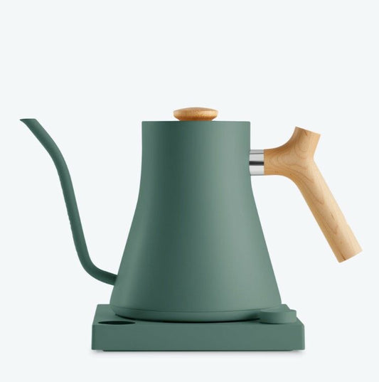 Fellow Stagg EKG 0,9 L elkedel i grøn har en præcisionstud med et langt, buet design og træhåndtag og -knop, alt sammen på en matchende base. Dens slanke, minimalistiske look kontrasterer smukt mod en subtil lysegrå baggrund.
