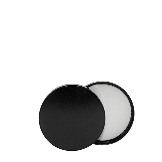 En sort, cirkulær kosmetikbeholder med låget på klem, med hvid creme eller balsam indeni, gengiver det slanke design af et Comandante Låg til Kaffebønne Glas fra Comandante, kendetegnet ved sin enkle og minimalistiske stil.