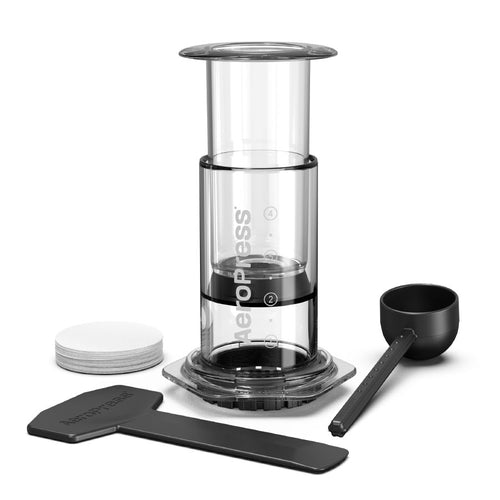 Et kompakt kaffebryggersæt fra Aeropress: AeroPress, Clear kaffebrygger med målemerker, scoop, rører, sort filterholder og papirfiltre - alt elegant arrangert mot hvit bakgrunn.