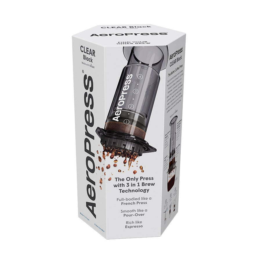En hvid, sekskantet æske viser en AeroPress Original kaffebrygger fra Aeropress med kaffe, der drypper ned i en kop, og en emballage, der fremhæver dens 3-i-1-brygningsteknologi, som giver en jævn, fyldig, espressolignende kaffeoplevelse.