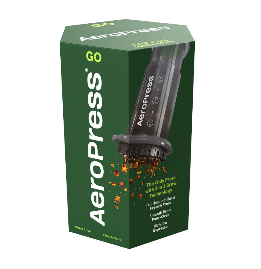 En grøn AeroPress, Go Travel kaffebryggerboks fra Aeropress, hvor kaffen sprøjter ud. Tekst: "Fyldig som en French Press, blød som Pour Over, rig som Espresso." Perfekt til rejser.