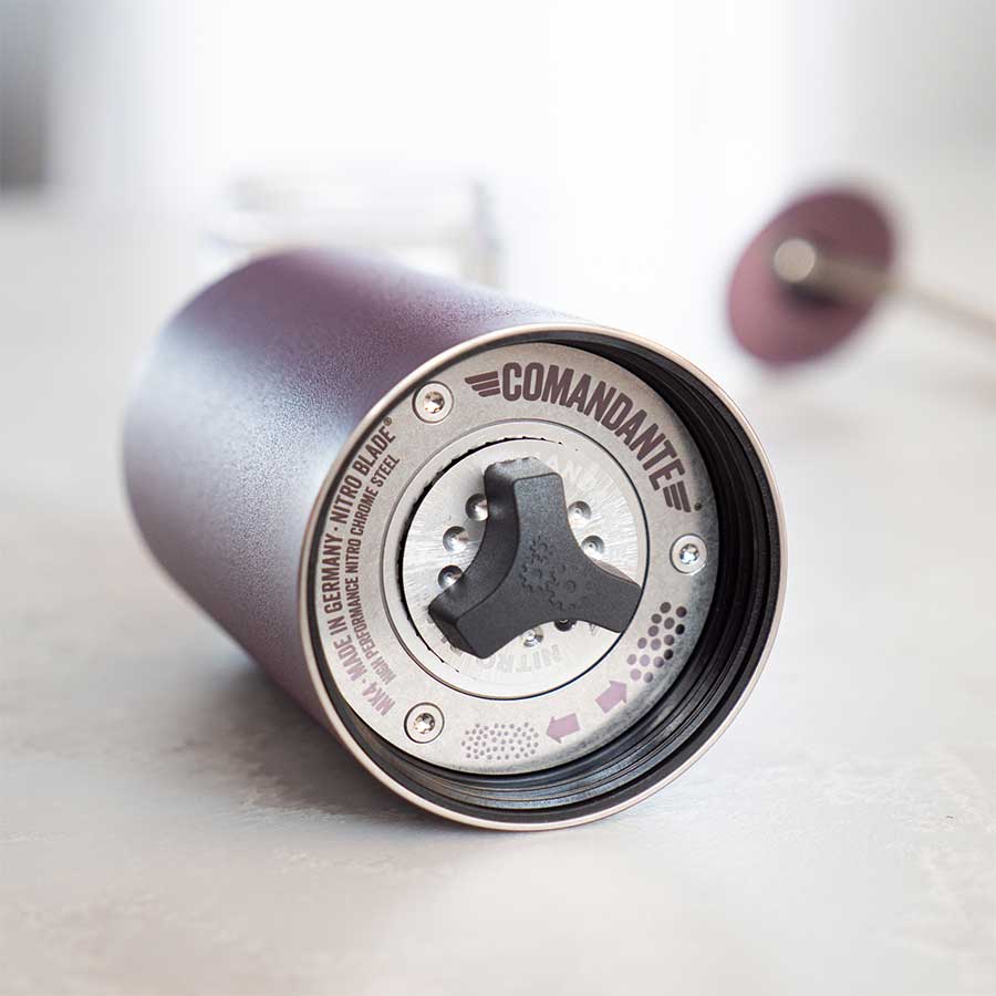 Nærbillede af Comandante C40 MK4 Nitro Blade, Deep Purple håndkværn. Justeringsknappen, de markerede maleindstillinger og stålkværnbladet er synlige gennem den matte og metalliske finish, når kværnen ligger på siden.
