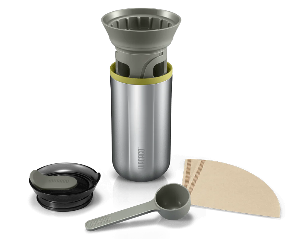 Wacaco Cuppamoka fra Wacaco er et transportabelt kaffebrygger-rejsekrus i rustfrit stål med en aftagelig dripper, sort låg, grøn scoop og keglefiltre, alt sammen vist på en hvid baggrund.