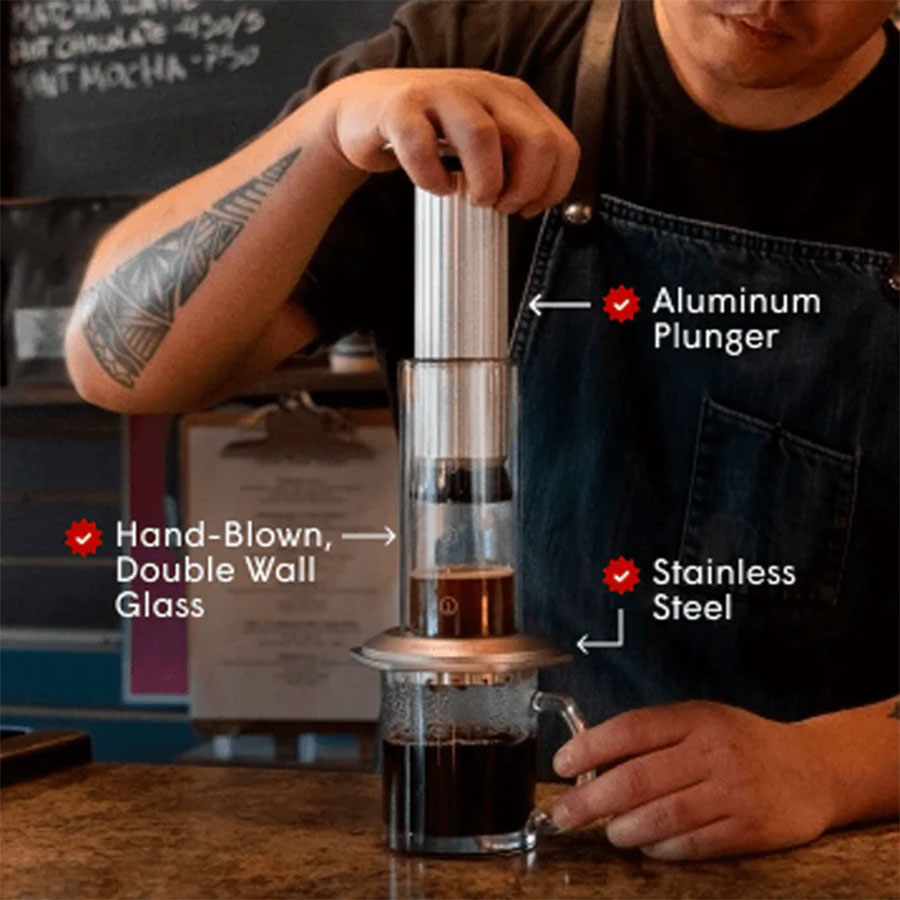 Nogen brygger kaffe med Aeropress Premium fra Aeropress, som har mærkede dele som et aluminiumsstempel, håndblæst dobbeltvægget glashus og et filter i rustfrit stål.