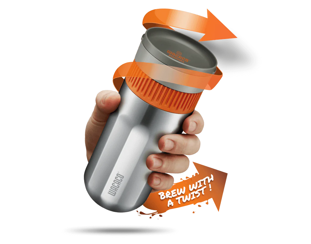 En hånd holder et Wacaco Pipamoka rejsekrus med orange låg, snoede pile og sætningen "BREW WITH A TWIST!", der viser, hvordan denne Wacaco nomadiske kaffemaskine bruges til at brygge på farten.
