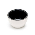 Rhino Coffee Gear, Cupping Skål har et blanksort interiør og mat hvidt ydre, der ligner SCA standard cupping skåle. Det er vist fra oven i en vinkel på en almindelig hvid baggrund.