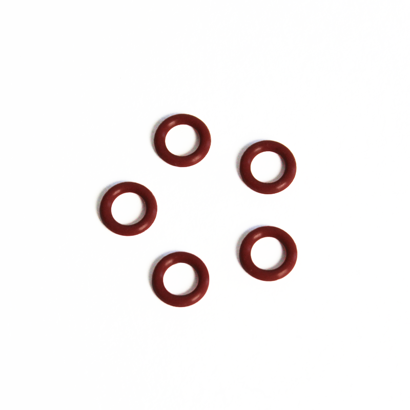 Fem røde silikoneringe fra Comandante Red Silicone Ring-sættet (5 stk.) fra Comandante, arrangeret i en løs cirkel på en hvid baggrund.