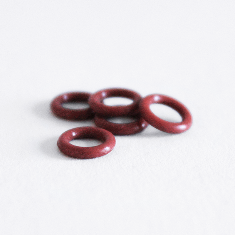 Fem Comandante Red Silicone Rings (5 stk.) ligger i en løs klynge på en hvid overflade og er ideelle som erstatningsringe til dit Comandante håndkværn.