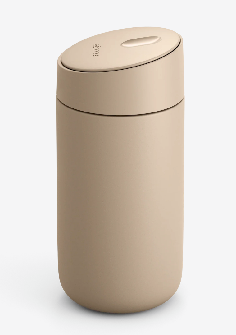 Fellow Carter Slide Mug er et beige, cylindrisk termokrus med en afrundet, mat finish, matchende låg med lille oval knap, keramisk belægning og ingen hanke eller synlig branding.