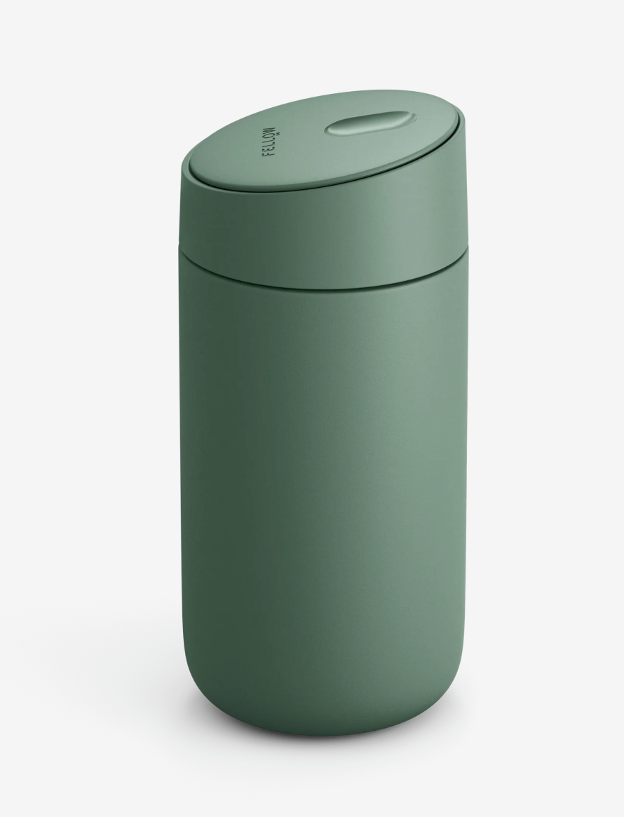 Et matgrønt, cylindrisk Fellow Carter Slide Mug termo krus med afrundet låg og oval knap på toppen, med keramisk belægning, er placeret på en ensfarvet hvid baggrund.