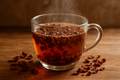 Et klart glaskrus fyldt med dampende Cascara Te (øko) fra EverBean ApS, omgivet af tørrede hibiscusblade og cascara te spredt på en træoverflade.