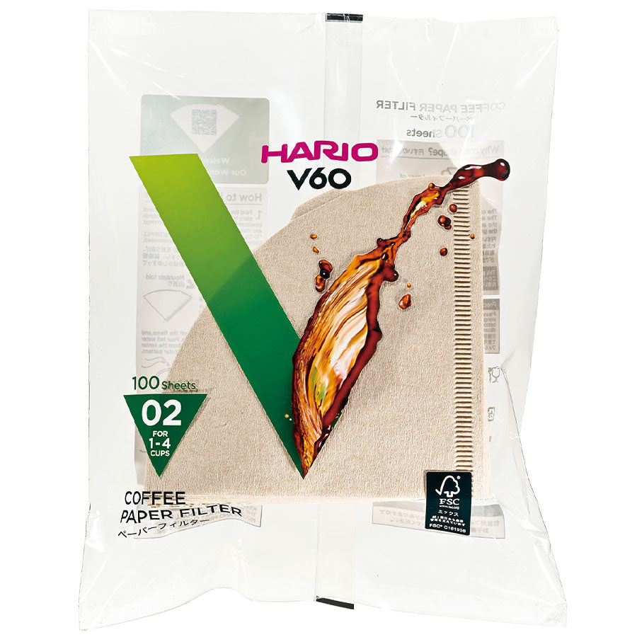 Hario Papirfiltre til V60 (100 stk), biologisk nedbrydelige, passer til 02-dripper (1-4 kopper). Emballagen har et grønt "V", kaffesplash-grafik og japansk tekst; delvist gennemsigtig.