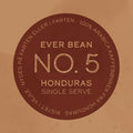 På en rund, brun etiket står der: "EverBean Wholesale Single Serve (w)" i midten, og rundt om kanten står der "100% Arabica kaffebønner fra Honduras", hvilket fremhæver denne limited kaffe som single origin kaffe på dansk.